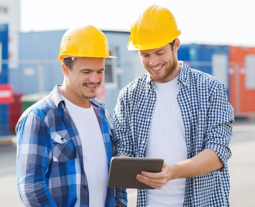 2 constructions workers looking at an iPad and smiling
